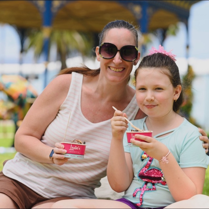 Mother and daughter enjoying desserts on the grass